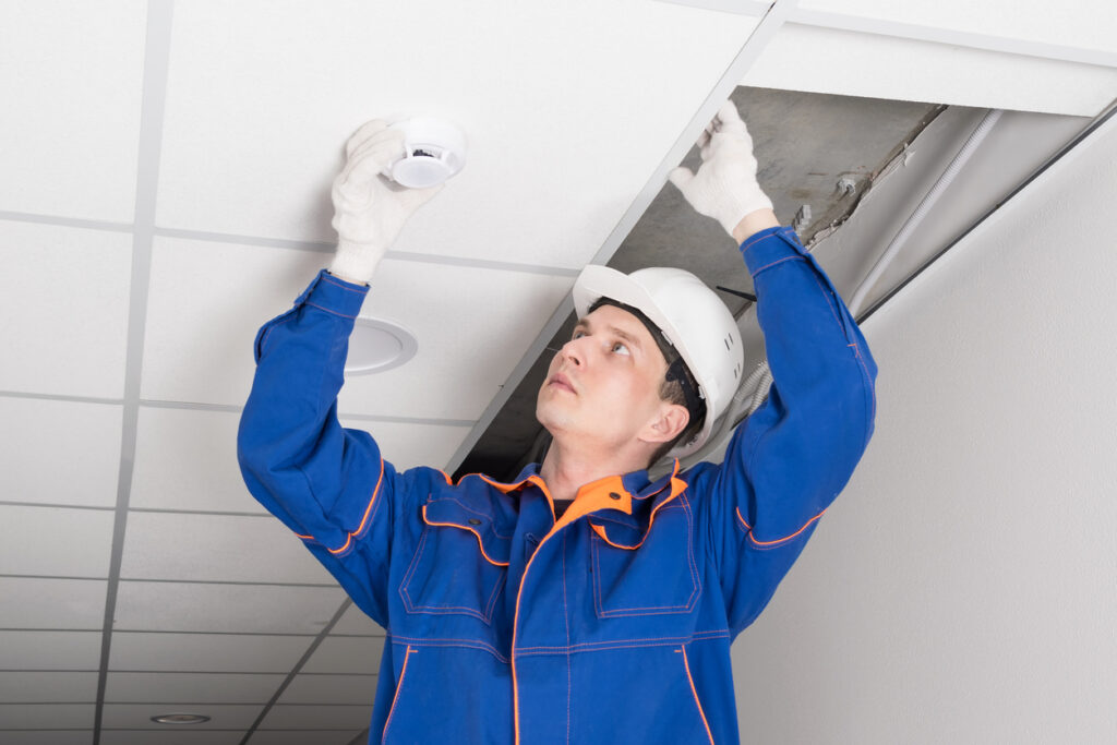 Worker installing an occupancy sensor on the ceiling